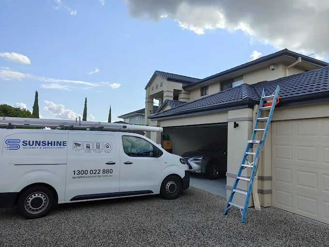 Sunshine Security van parked at a home with a ladder up to the roofline