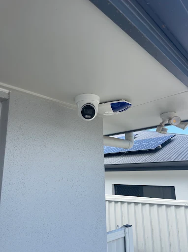 Neatly installed security camera and alarm siren under an eave