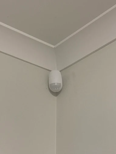 Motion sensor neatly installed in the corner of a room ceiling